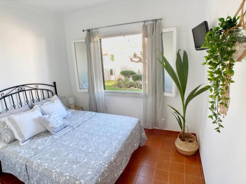 1 dormitorio con cama y ventana en La Casa del Jardin. Menorca, en Punta Grossa