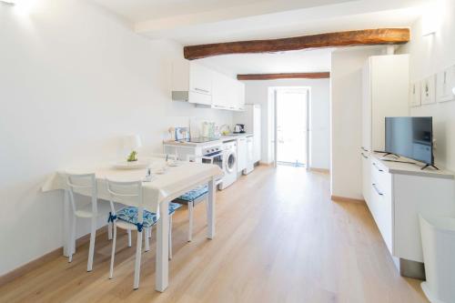 a white kitchen with a white table and chairs at 105 - La Casa di Jacopo, fronte e vista mare in centro a Riva Trigoso, 20 metri dalla spiaggia in Sestri Levante