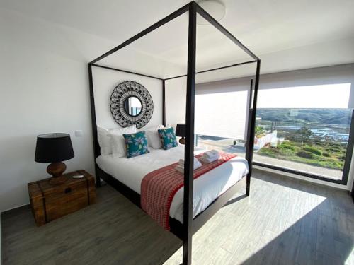 a bedroom with a canopy bed with a large window at Cairnvillas Villa Flow C40 Luxury Villa with Private Swimming Pool near Beach in Aljezur