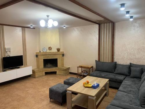 een woonkamer met een bank en een open haard bij Tsaghkadzor Villa in Tsachkadzor