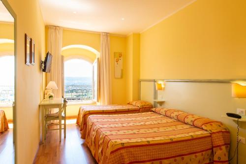 a hotel room with two beds and a window at Hotel Minerva in Assisi