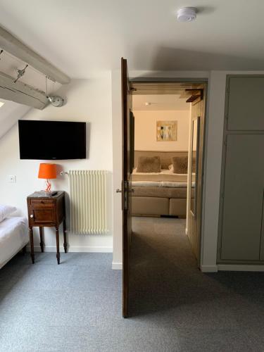 a room with a bedroom with a bed and a television at Hotel SPA Au Cheval Blanc in Ribeauvillé