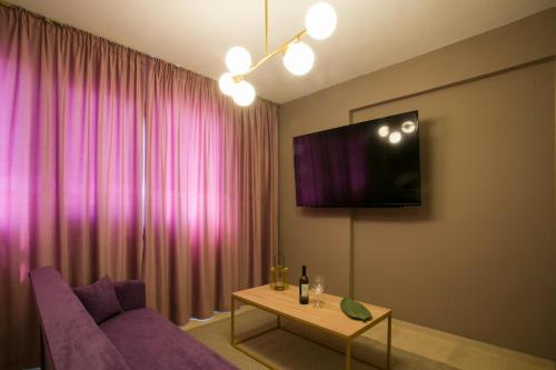 a living room with a purple couch and a tv at Marizas luxury suites #1 in Thessaloniki