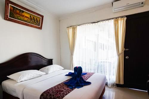 a bedroom with a bed with a blue ribbon on it at Taman Ayu Legian Hotel in Legian