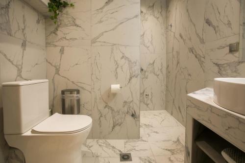a white bathroom with a toilet and a sink at Marizas luxury suites #1 in Thessaloniki