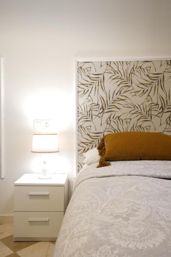 a bedroom with a bed and a nightstand with a lamp at ADANAR-Las Columnas in Granada