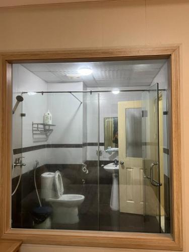 a glass window of a bathroom with a toilet and sink at Can ho Muong Thanh in Cửa Lò