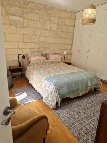 a bedroom with a large bed and a chair at Les Arènes in Arles