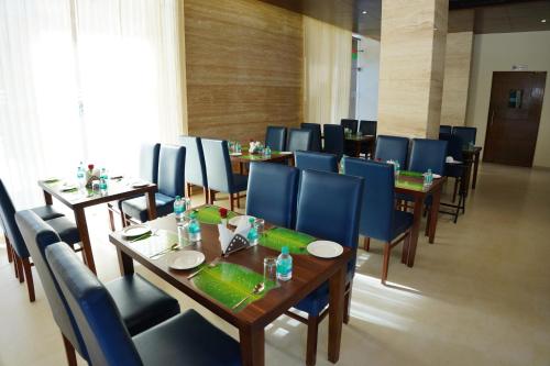 a dining room with wooden tables and blue chairs at The Ocean Pearl Dharmasthala Ujire in Dharmastala