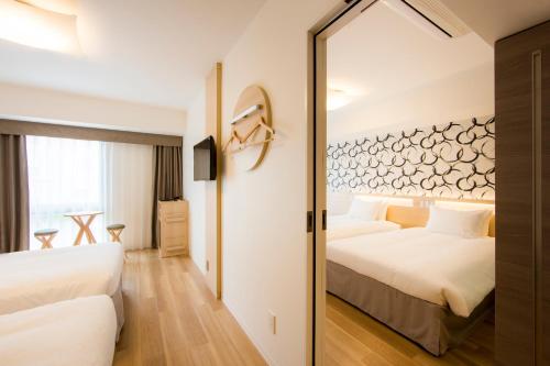 a hotel room with two beds and a mirror at Karaksa Hotel Osaka Namba in Osaka