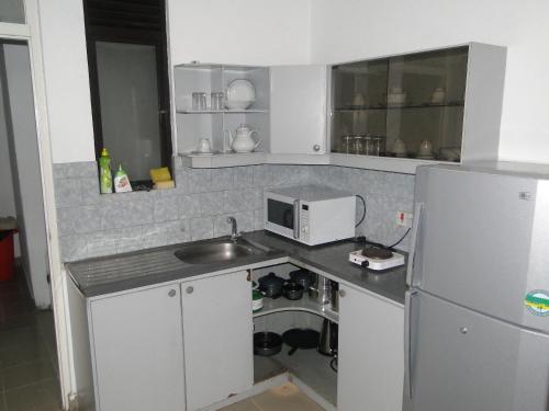 a kitchen with a sink and a microwave and a refrigerator at BRAMA Station Court {Apartment} in Colombo