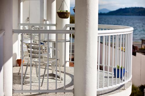 a balcony with chairs and tables and the water at Lakeside Taupo Motel in Taupo
