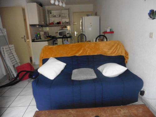 - un canapé bleu avec trois oreillers dans la cuisine dans l'établissement appartement, à Saint-Cyprien
