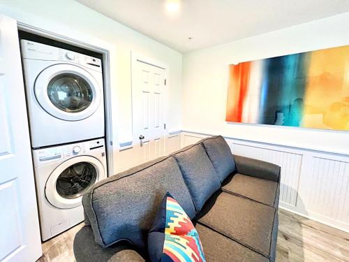 a living room with a couch and a washer and dryer at 302 Queen Suite, 3rd Floor Low Tide in Surf City