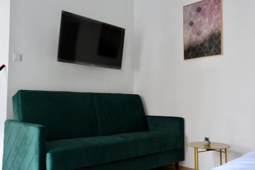 zieloną kanapę w salonie z telewizorem w obiekcie Narutowicza 5 Apartments w mieście Inowrocław