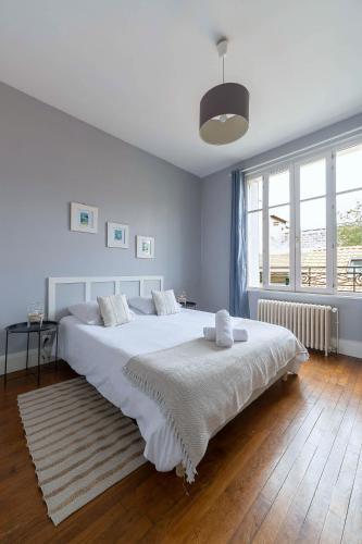 une chambre avec un grand lit blanc avec une grande fenêtre dans l'établissement Residence Le Languedoc - Appartements design - Proche des parcs, à Vichy