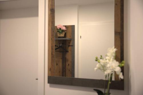 a mirror on a wall with a vase of flowers at Sorinas Home WB16 Top 12 in Wagersbach