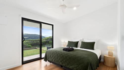 a white bedroom with a bed and a large window at Glen Tara in Johanna