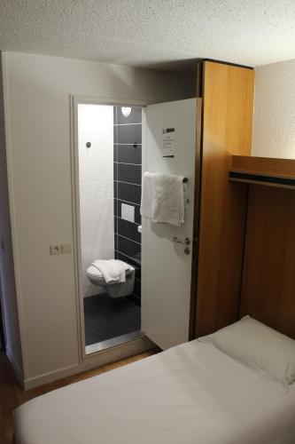 a small bathroom with a bed and a shower at Brit Hotel La Bonne Etape in Évreux