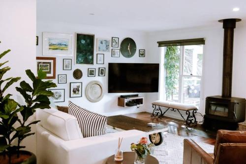 a living room with a white couch and a flat screen tv at The Grange country retreat, with a birds eye view! in Mittagong