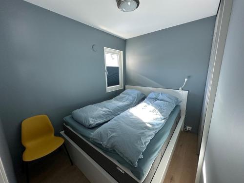 a small bedroom with a bed and a yellow chair at Sinnestunet 201A in Tjørhom