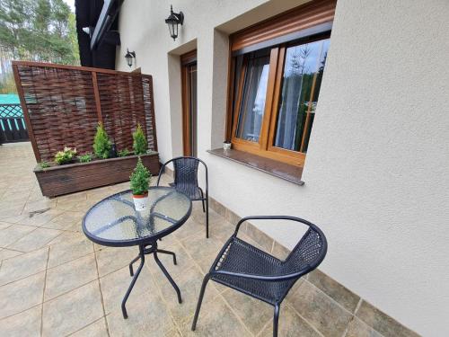 a patio with a glass table and two chairs at Apartamenty "Hubertówka" 