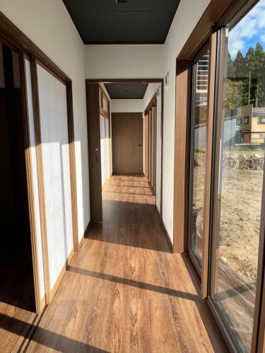 a corridor of a house with wooden floors and windows at ミロクハウス in Daisen
