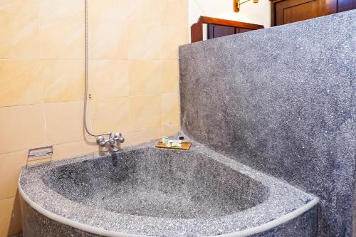 a bath tub with a faucet in a bathroom at Taman Ayu Legian Hotel in Legian