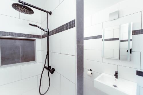 a shower in a bathroom with white tiles at Restaurant und Pension Alberthafen in Dresden