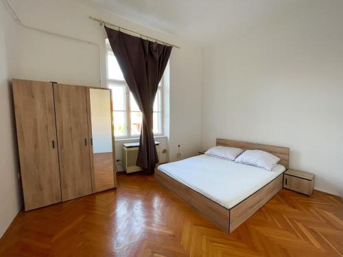 a bedroom with a bed and a large window at Centrum Hostel in Pécs