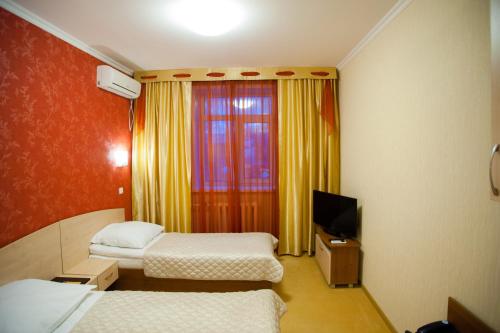 a hotel room with two beds and a television at Mereke Hotel in Ustʼ-Kamenogorsk