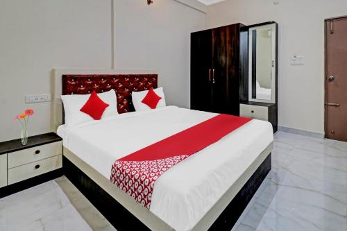 een slaapkamer met een groot wit bed met rode kussens bij OYO Nra Residency Near Rajarajeshwari Nagar Metro Station in Bangalore