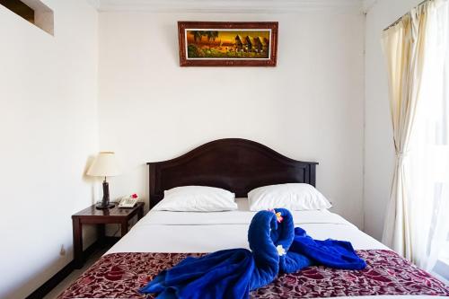 a bedroom with a bed with blue robes on it at Taman Ayu Legian Hotel in Legian