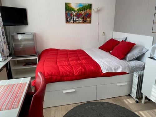 een slaapkamer met een rood bed en een televisie bij Valckesteyn in Poortugaal