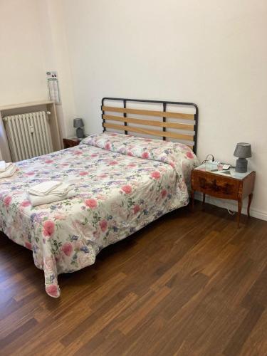 a bedroom with a bed with a floral blanket and a table at Benedettine in Verona