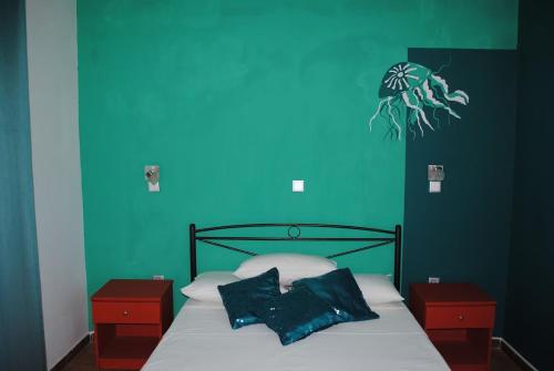 a bedroom with a blue wall and a bed with two pillows at Karmik Concept Apartments in Afantou