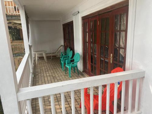 a balcony with green chairs and a red door at Lippo Carita Beach Utara Condo Noah in Carita