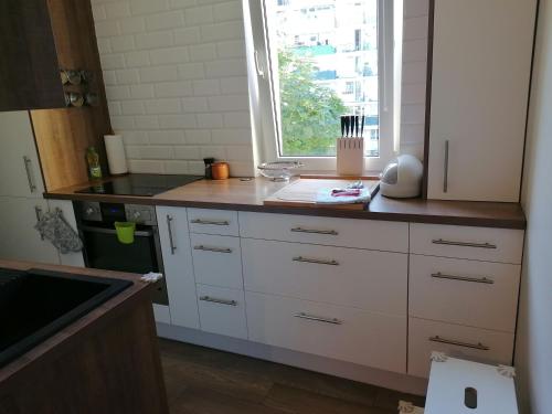 a kitchen with white cabinets and a window at Books Apartments- blisko morza in Gdańsk
