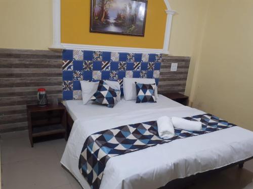 a bedroom with a bed with blue and white pillows at Hotel Ishan in Katra