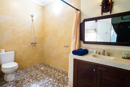a bathroom with a toilet and a sink and a mirror at Taman Ayu Legian Hotel in Legian