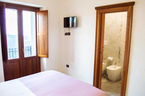 a bedroom with a bed and a bathroom with a toilet at Palazzo Iaquinta - Rooms, Restaurant & Wellness in Cicerale