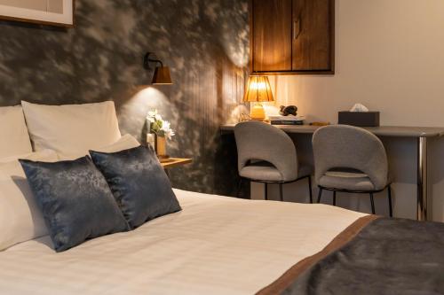 a hotel room with a bed with two chairs at Bijou Suites Classic in Osaka