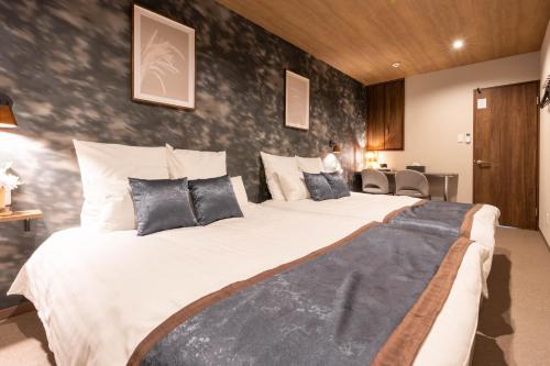 a bedroom with a large white bed with black pillows at Bijou Suites Classic in Osaka