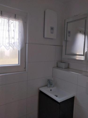 een badkamer met een wastafel, een spiegel en een raam bij Bungalow am Schwielochsee in Schwielochsee