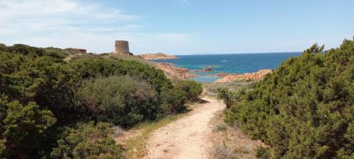 a dirt road with a castle on a hill next to the ocean at piccolo monolocale al porticciolo in Isola Rossa