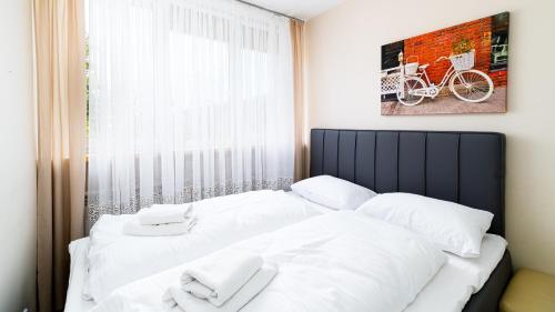 1 dormitorio con 1 cama con sábanas blancas y ventana en Apartamenty Sun & Snow Korczaka, en Świeradów-Zdrój