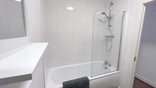 a white bathroom with a shower with a glass door at Friars House, Stafford by BELL Apartments in Stafford