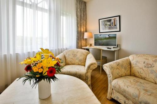 uma sala de estar com duas cadeiras e um vaso de flores em Villa Edda - Ferienapartment 28 em Graal-Müritz