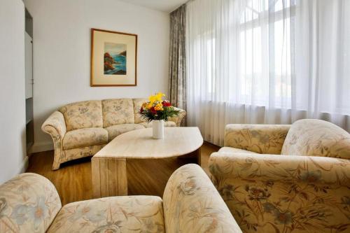 uma sala de estar com dois sofás e uma mesa com flores em Villa Edda - Ferienapartment 28 em Graal-Müritz
