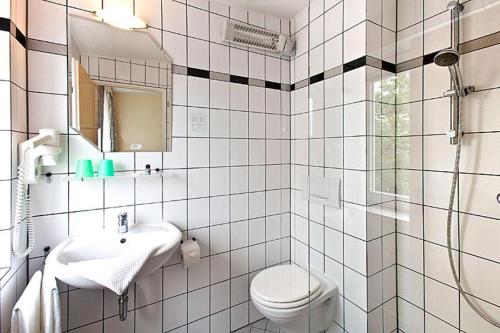 uma casa de banho em azulejos brancos com um WC e um lavatório em Villa Edda - Ferienapartment 28 em Graal-Müritz